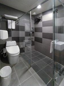 a bathroom with a toilet and a glass shower at Hotel J Taoyuan in Pingzhen