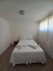 1 dormitorio con cama blanca y ventana en Suíte privativa na Barra da Tijuca proxima à praia, en Río de Janeiro