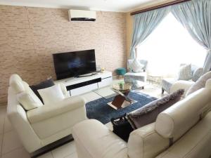 a living room with white furniture and a flat screen tv at Hidden Gem in Marian Downs in Pinetown