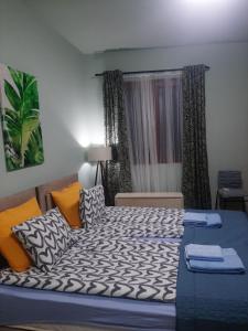 1 dormitorio con 1 cama grande con almohadas de color naranja y azul en Apartman Ana en Leskovac