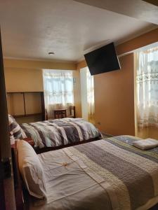 a bedroom with two beds and a flat screen tv at Hostal Capac in Ayacucho