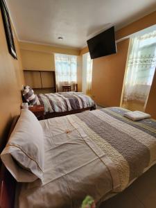 a bedroom with two beds and a flat screen tv at Hostal Capac in Ayacucho