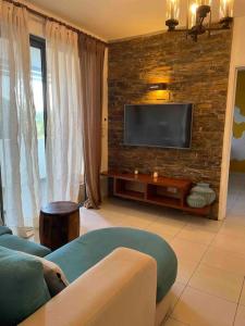 a living room with a tv on a brick wall at Beautiful 3 rooms apartment, 2 beds & 1 dressing room in Flic-en-Flac