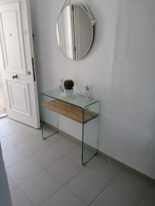a glass table with a mirror on a wall at Apartamento Rota in Rota