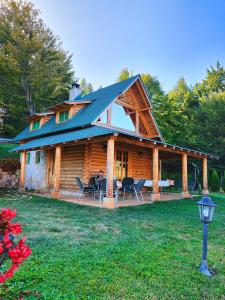 a log cabin with a porch and chairs in the yard at Vila Maja in Rudno