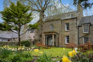 een oud stenen huis met een tuin met bloemen bij Pentland Hotel in Thurso