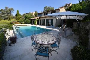 einen Tisch und Stühle mit einem Sonnenschirm neben einem Pool in der Unterkunft Haute Vue - Luxury Villa - Private Pool & Panoramic View in Montauroux