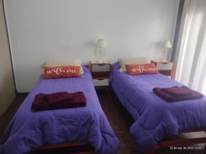 two beds in a room with purple sheets and pillows at Buenos Aires, CABA in Buenos Aires