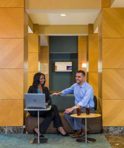a man and a woman sitting on a bench with a laptop at DoubleTree by Hilton Chicago - Arlington Heights in Arlington Heights