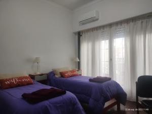 - une chambre avec 2 lits avec des draps violets et une fenêtre dans l'établissement Buenos Aires, CABA, à Buenos Aires
