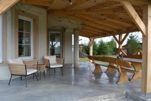a covered patio with chairs and a table and a bench at Domek mamy in Tykocin