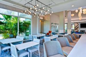 a waiting room with tables and chairs and a chandelier at Hilton Garden Inn Jacksonville Orange Park in Orange Park
