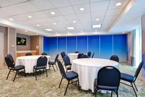 Hilton Garden Inn Jacksonville Orange Park في أورانج بارك: قاعة المؤتمرات مع الطاولات والكراسي والجدران الزرقاء