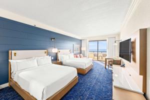 Hilton Sandestin Beach Golf Resort & Spa في ديستين: غرفه فندقيه سريرين وجدار ازرق