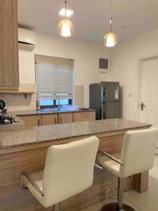 a kitchen with two white chairs at a counter at Beautiful 3 rooms apartment, 2 beds & 1 dressing room in Flic-en-Flac