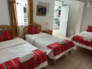 a bedroom with two beds with red and white blankets at Hotel Plateros in Cusco