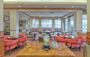 ein Restaurant mit orangefarbenen Stühlen, Tischen und Fenstern in der Unterkunft Hilton Garden Inn Laramie in Laramie