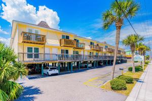 ein großes gelbes Gebäude mit Balkonen und einer Palme in der Unterkunft Sand Dollar #14 in Gulf Shores