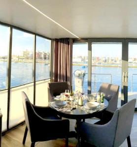 a dining room with a table and chairs and a large window at Hausboot Luv in Flensburg