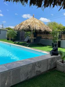 a villa with a swimming pool and a straw umbrella at Palmhouse Apartments Aruba 1- 4 persons in Savaneta