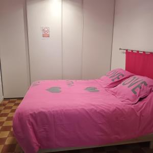 ein rosa Bett mit einer rosa Bettdecke in einem Zimmer in der Unterkunft La petite maison Lavandin 