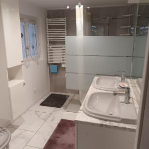 a white bathroom with a sink and a shower at La petite maison Lavandin 