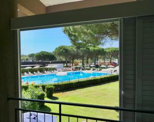 uma vista para uma piscina a partir de uma janela em ISA-Apartment 3 beds in Residence with swimming-pool bed and bath linen included em Marina di Bibbona