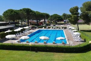 uma grande piscina com guarda-sóis e cadeiras brancas em ISA-Apartment 3 beds in Residence with swimming-pool bed and bath linen included em Marina di Bibbona