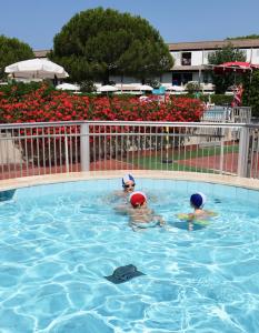três pessoas estão nadando em uma piscina em ISA-Apartment 3 beds in Residence with swimming-pool bed and bath linen included em Marina di Bibbona
