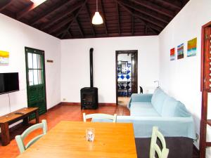 een woonkamer met een tafel, een bank en een fornuis bij La Bodega casa rural con piscina y jardines in Breña Baja