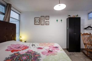 ein Schlafzimmer mit einem Bett mit Blumenbettdecke in der Unterkunft Cuarto Yaqui - Seguridad - 10 min de Centros Comerciales y Zona Esmeralda - Empresas bienvenidas in Mexiko-Stadt