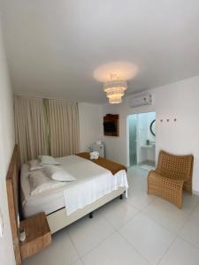 1 dormitorio con 1 cama grande y 1 silla en Monte Alegre Beach, en São Miguel do Gostoso