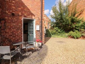 a brick building with a table and chairs next to a door at The Old Sweet Shop in Melton Mowbray