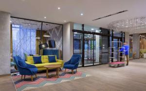 een lobby met een gele bank en blauwe stoelen bij Hampton By Hilton Astana Triumphal Arch in Astana