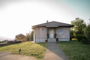 una pequeña casa blanca con un patio de césped en Zlatni Prag - Kraljevo en Kraljevo