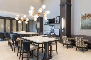 une salle à manger avec des tables et des chaises ainsi qu'un lustre dans l'établissement Hampton Inn & Suites Indianapolis-Keystone, IN, à Indianapolis