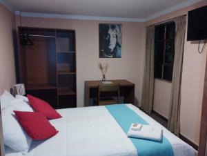 a bedroom with a large white bed with red pillows at Huaytusive Inn Hotel in Puno