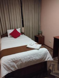 a hotel room with a bed with a red pillow at Huaytusive Inn Hotel in Puno