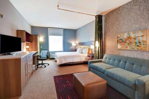 um quarto de hotel com uma cama, um sofá e uma televisão em Home2 Suites by Hilton Springfield North em Springfield