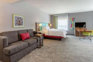 Hampton Inn & Suites Burlington في برلينغتون: غرفة في الفندق مع أريكة وسرير