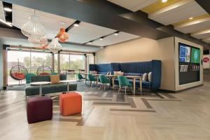 una sala de espera con mesas, sillas y TV en Tru By Hilton Charlotte Ayrsley en Charlotte