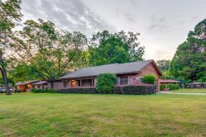 a house with a green yard in front of a house at Spacious Little Rock Home with Patio - 9 Mi to Dtwn! in Little Rock