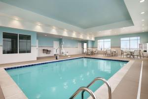 尚佩恩Hampton Inn Champaign Southwest的酒店里的游泳池，配有桌椅