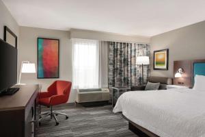 尚佩恩Hampton Inn Champaign Southwest的一间配有床、书桌和椅子的酒店房间