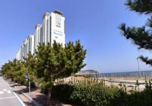 a large white building with trees in front of a beach at Ocean & sunrise View-10 seconds of beach walk - Three bedrooms in Goseong