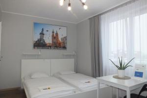 a room with two beds and a table and a window at Apartamenty Nila in Kraków