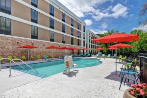 a pool with chairs and umbrellas in front of a building at Home2 Suites By Hilton Beaufort in Beaufort