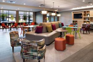 een lobby met een bank en tafels en stoelen bij Home2 Suites By Hilton New Albany Columbus in New Albany