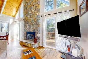 sala de estar con chimenea de piedra y TV de pantalla plana en Doris in the Forest, en Arnold