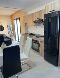 ララシュにあるCozy appartementのキッチン(黒い冷蔵庫、白い椅子付)